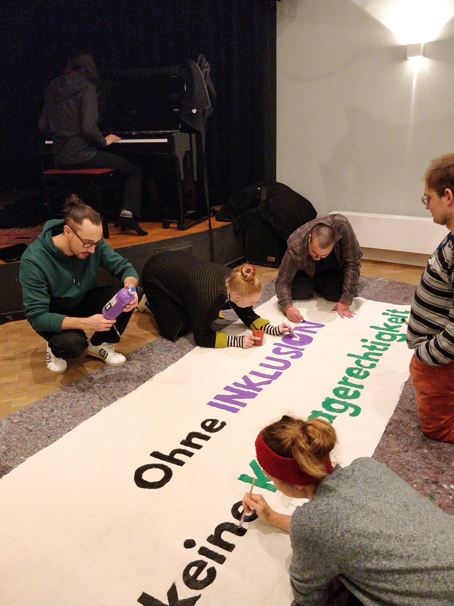 Menschen vom Aktionsbündnis Inklusion gestalten gemeinsam ein Transparent für eine Demonstration.